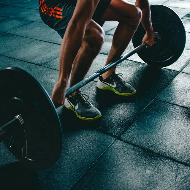 Person in athletic gear performing a deadlift on a gym floor