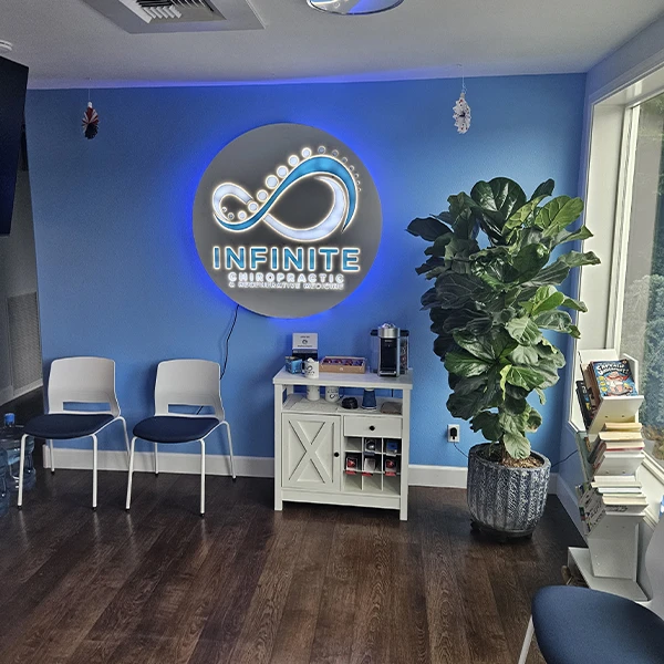 Waiting area of Infinite Chiropractic with a bright blue feature wall displaying a glowing infinity logo and clinic name